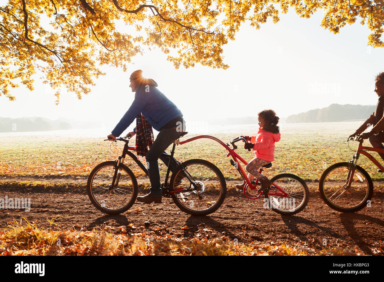 Vater und Tochter Fahrrad fahren mit Anhänger Fahrrad im sonnigen Herbst park Stockfoto