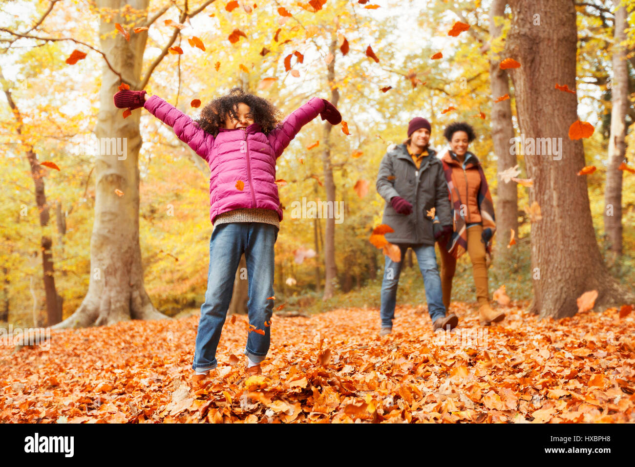 Verspielte Mädchen werfen Herbst Blätter im Wald Stockfoto