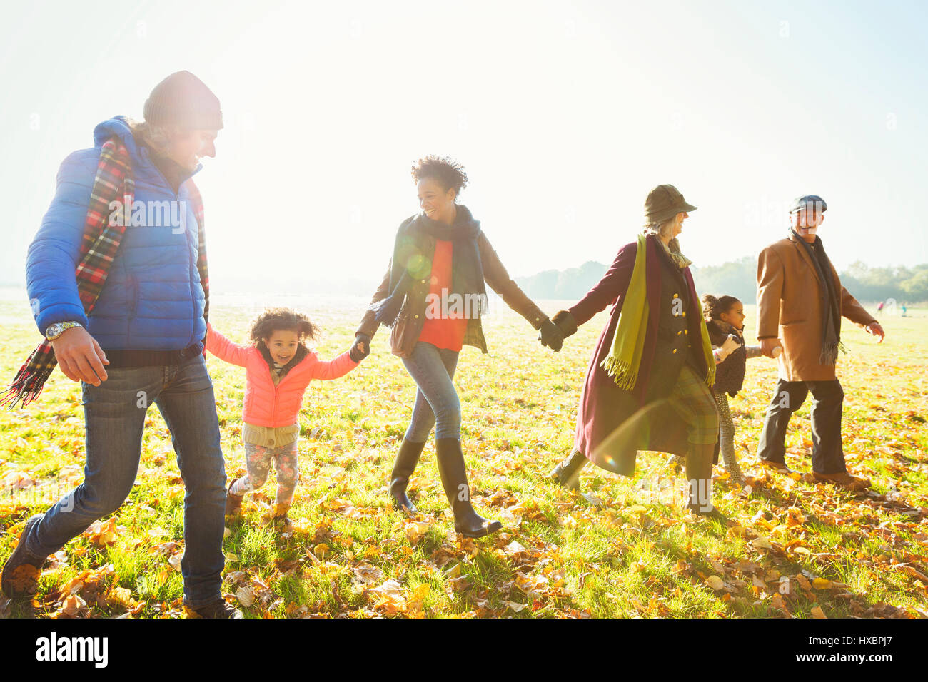 Familie Hand in Hand Wandern im sonnigen Herbst park Stockfoto