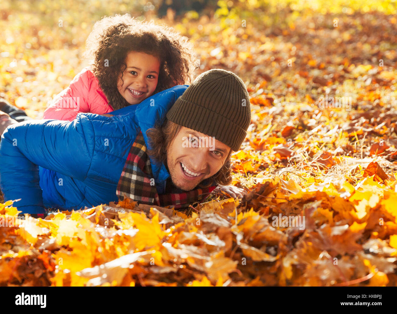 Porträt verspielte Tochter Handauflegen Vater im Herbst Blätter im sonnigen park Stockfoto