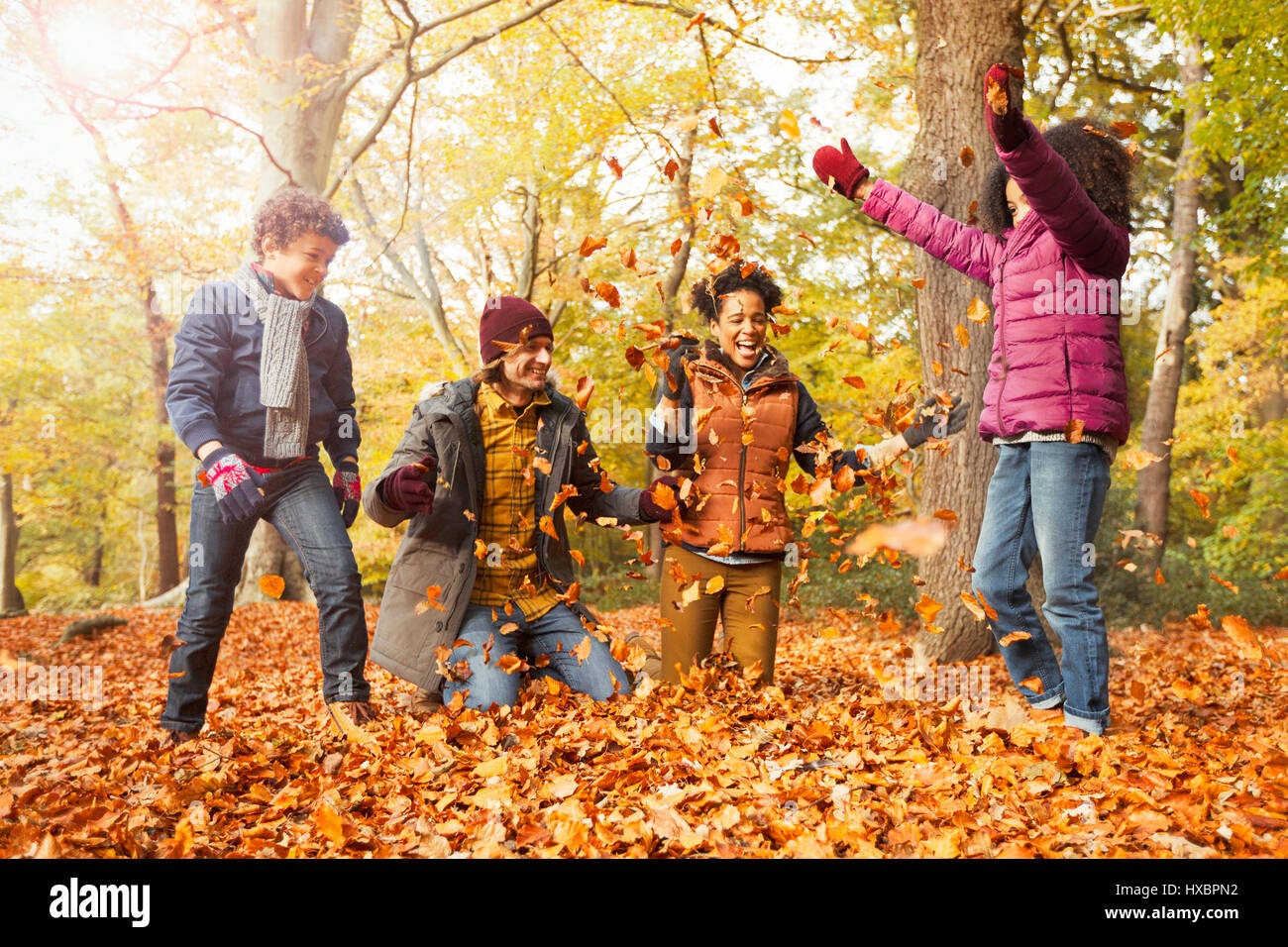 Verspielte junge Familie wirft Blätter im Herbst Wald Stockfoto