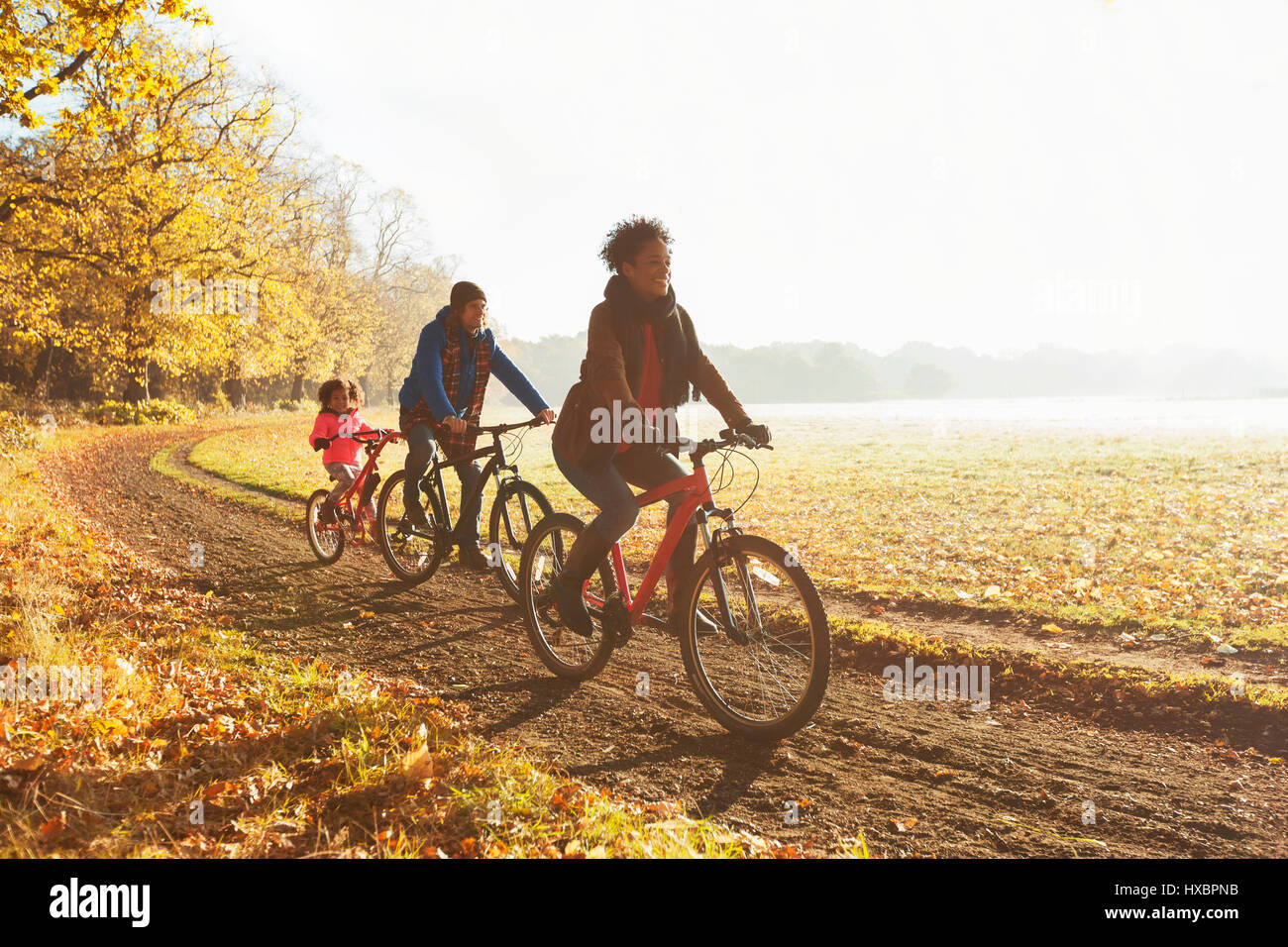 Verspielte junge Familie Radfahren auf Pfad im sonnigen Herbst park Stockfoto
