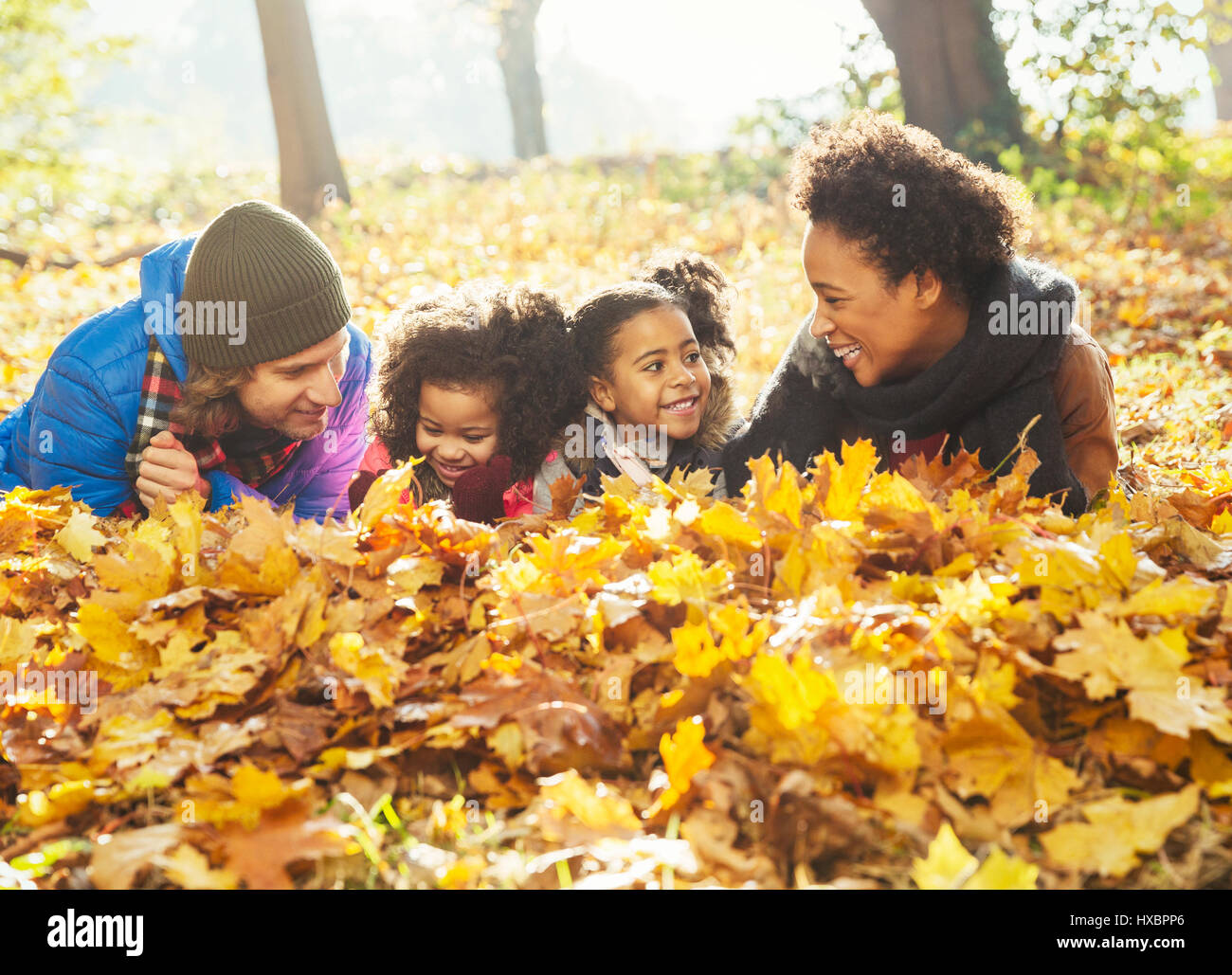 Verspielte junge Familie im Herbst verlegen lässt im sonnigen Wald Stockfoto
