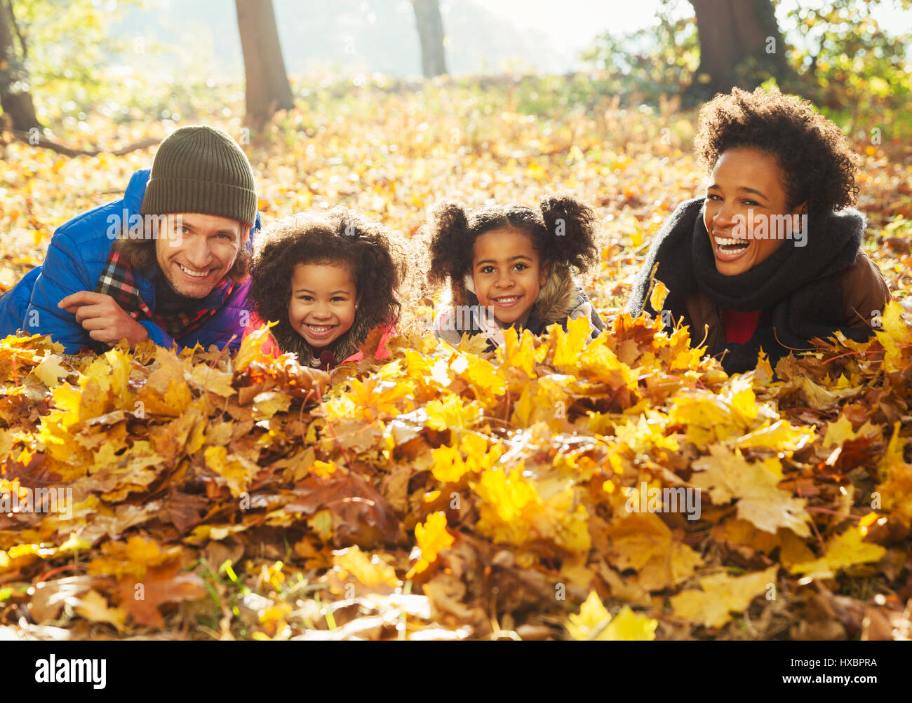 Porträt, Lächeln, junge Familien legen im Herbst Blätter im sonnigen Wald Stockfoto
