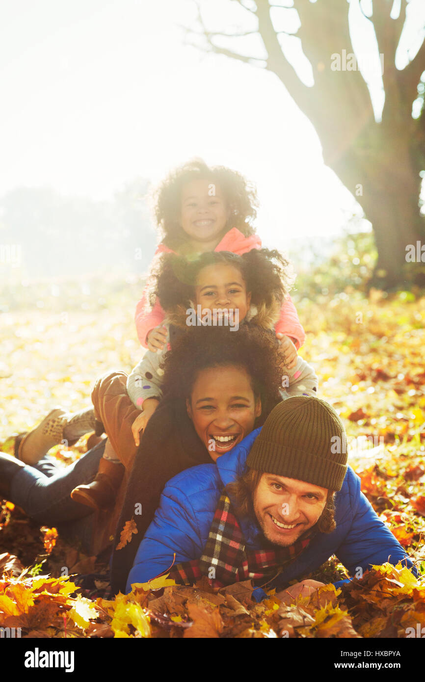 Porträt, lächelnde junge Familie Verlegung übereinander im sonnigen Herbst Blätter Stockfoto