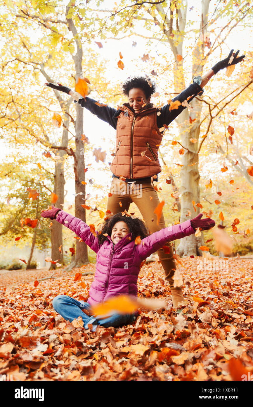 Spielerische Mutter und Tochter werfen Herbstlaub im park Stockfoto