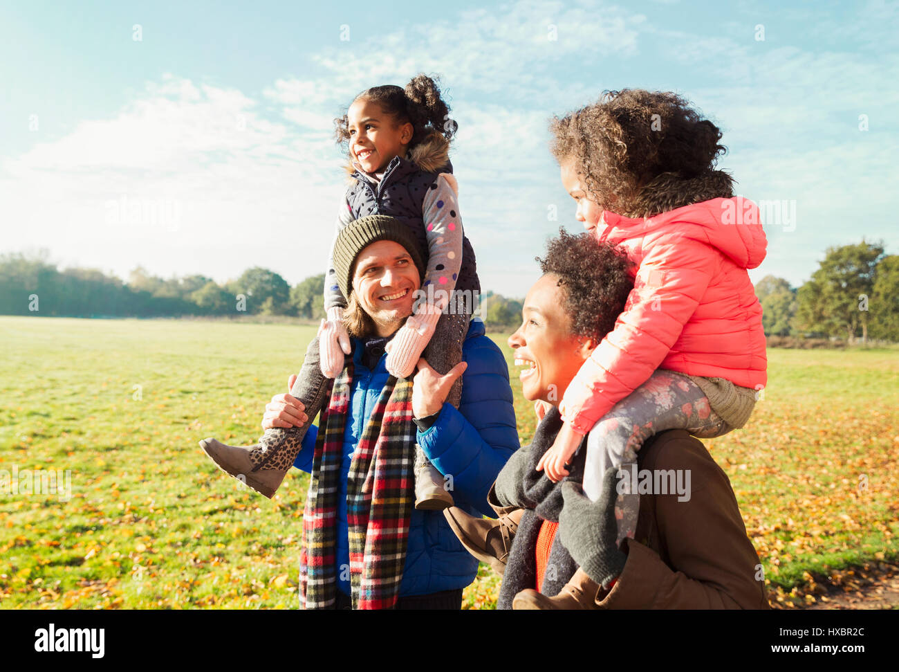 Eltern tragen Töchter auf Schultern im sonnigen Herbst park Stockfoto
