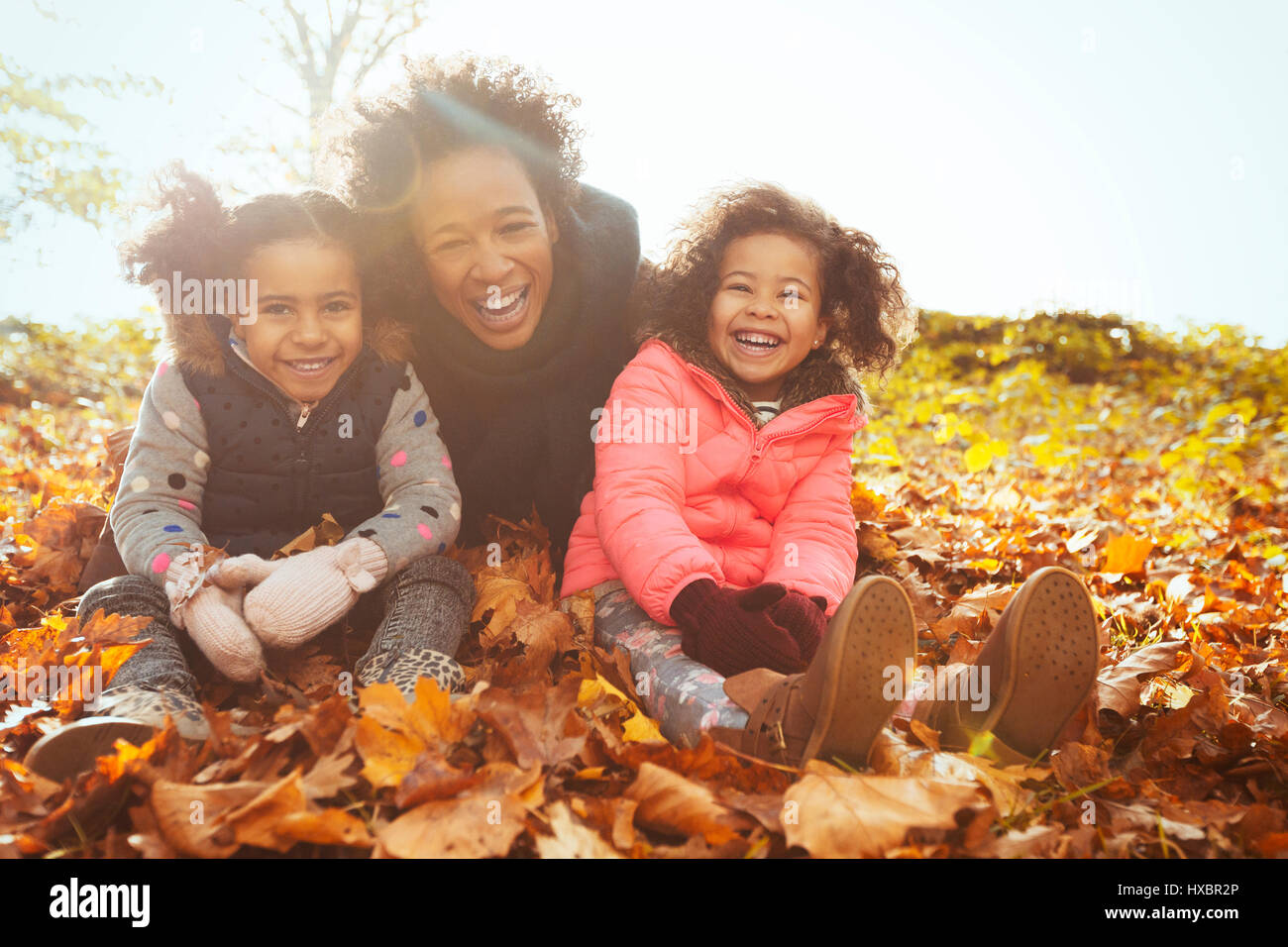 Porträt spielerische Mutter und Töchter im Herbstlaub im sonnigen park Stockfoto