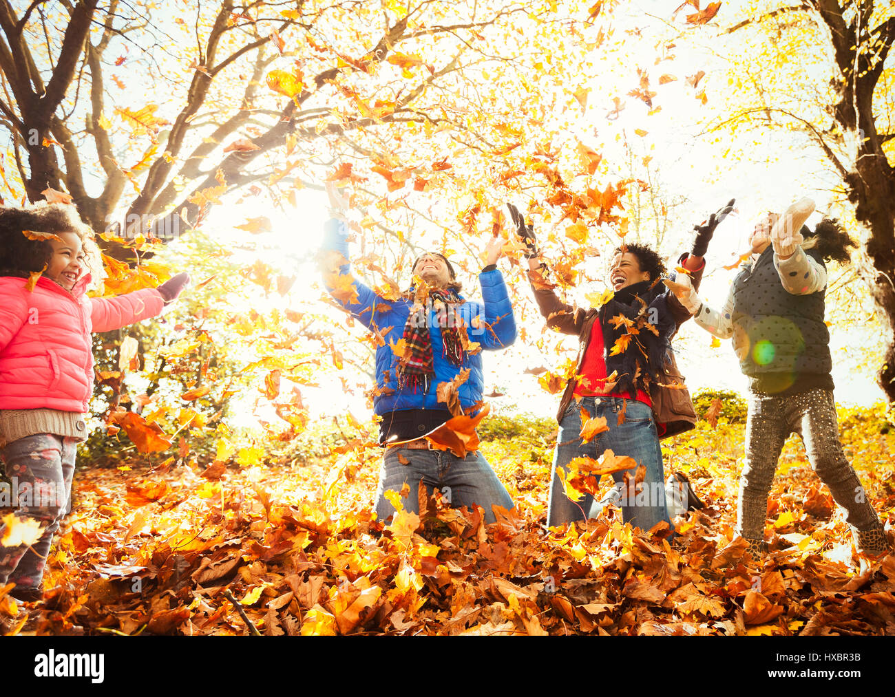 Verspielte junge Familie werfen Herbst Blätter im sonnigen park Stockfoto