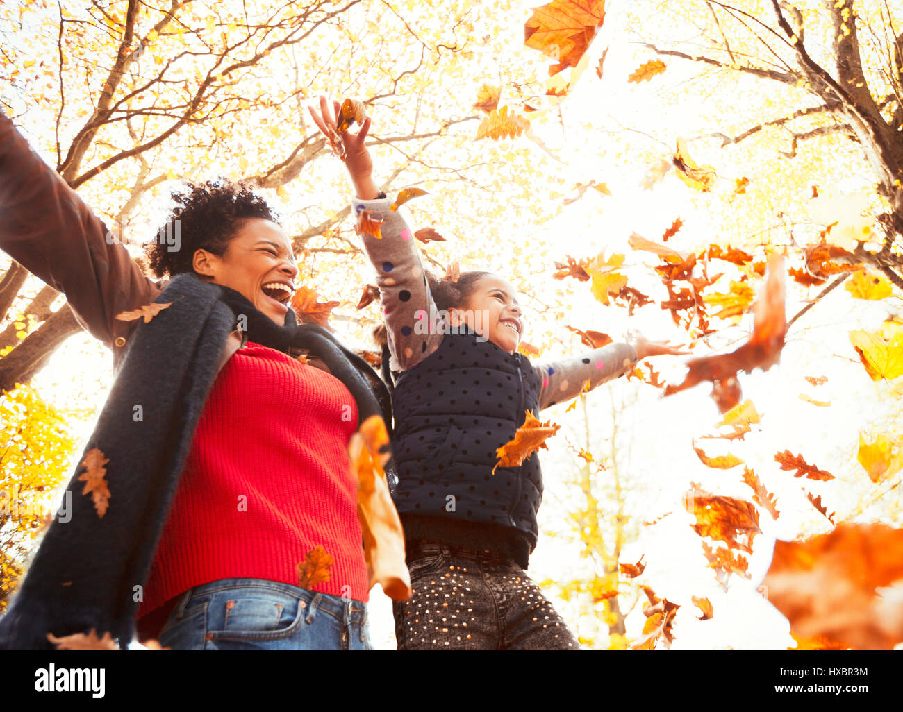 Spielerische Mutter und Tochter werfen Herbstlaub im sonnigen park Stockfoto