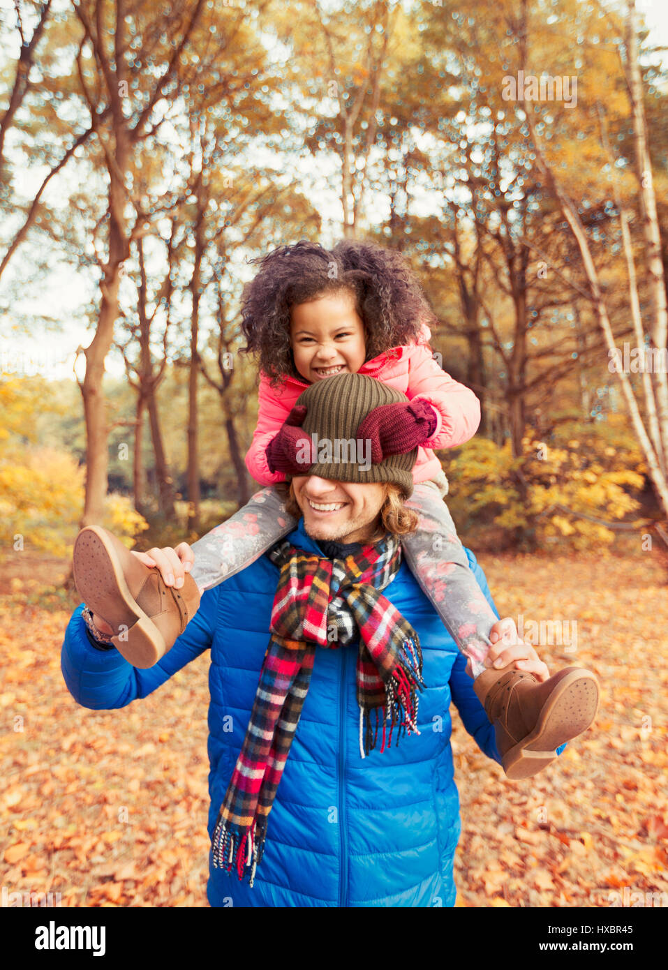 Porträt verspielte Tochter ziehen Zipfelmütze über Väter Augen im Herbst park Stockfoto