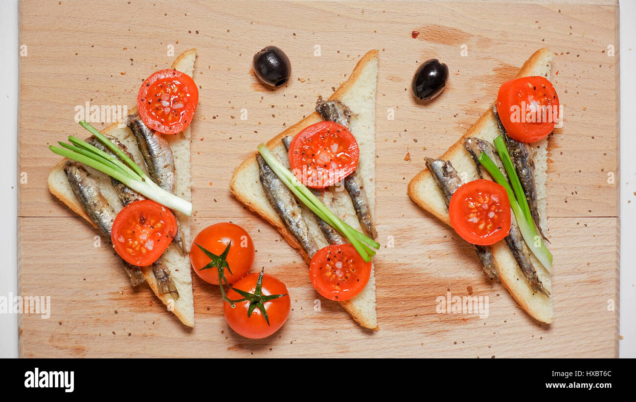 Dreieckige Sandwiches mit Sardinen, Sprotten, Cherry-Tomaten und grüne Zwiebeln, Oliven Stockfoto