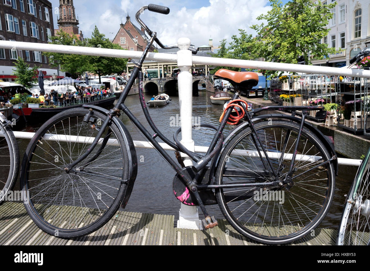 altes Fahrrad geparkt am holländischen Kanal Stockfoto