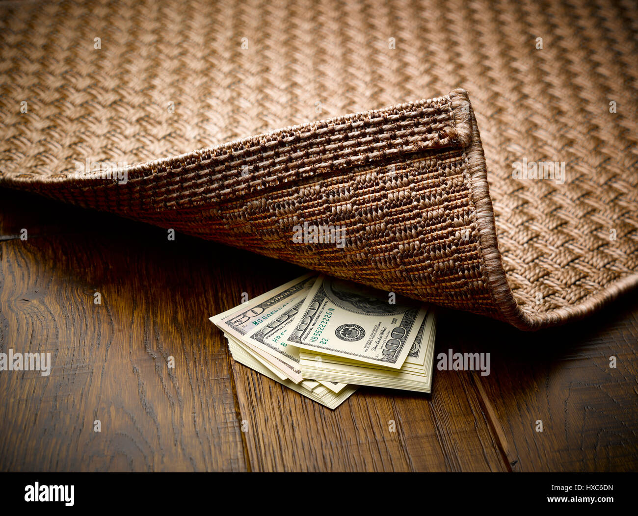 Geld versteckt unter Teppich Stockfoto