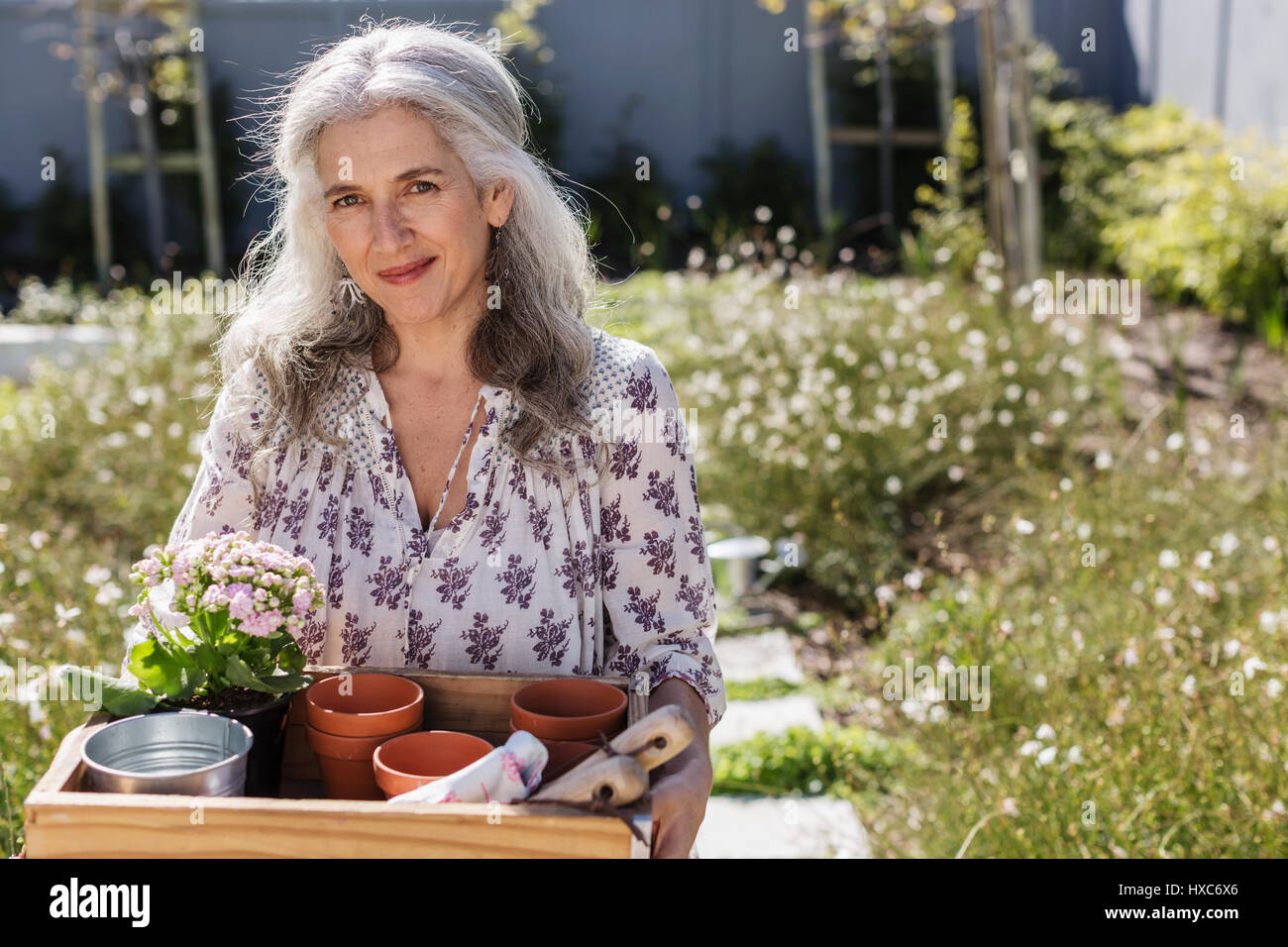 Reife Frau Porträt mit Gartenarbeit Tablett im sonnigen Garten Stockfoto