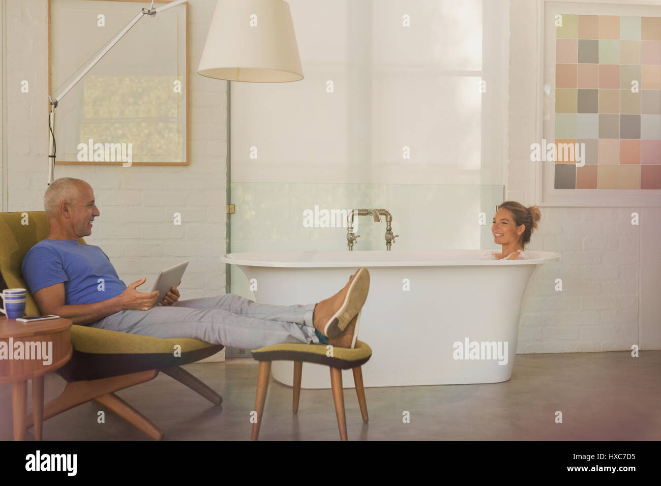 Mann mit digital-Tablette entspannen, im Gespräch mit Frau in der Badewanne in luxuriösen Hotelzimmer Stockfoto