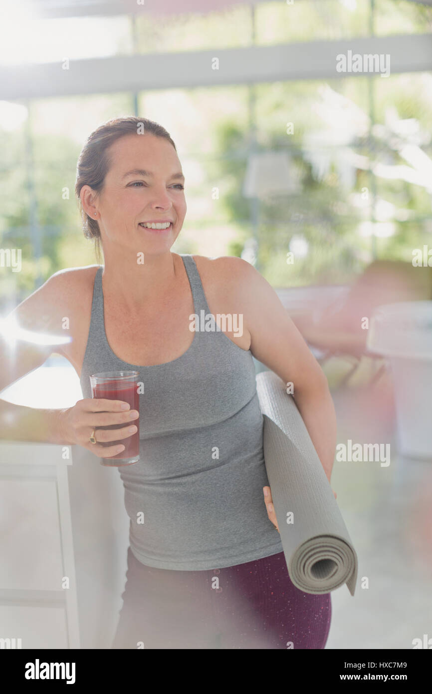 Lächelnd Reife Frau mit Yoga-Matte, trinken gesunde Frucht-smoothie Stockfoto