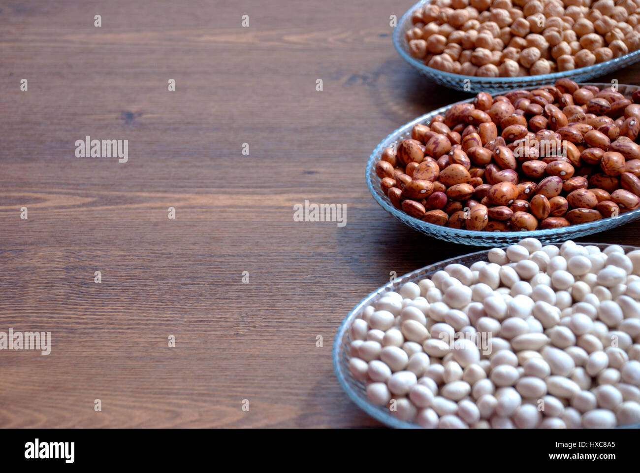 Impulse in einer Schüssel auf einem Holztisch für Bacgrounds (Gartenbohnen Bohnen, Kidney-Bohnen und Kichererbsen) Stockfoto