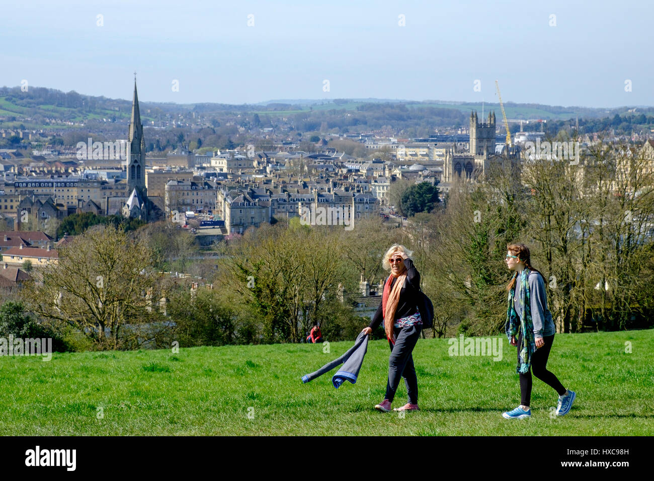 Zwei Wanderer / Spaziergänger sind abgebildet, zu Fuß auf Bathwick Hill mit Blick auf die Stadt Bath, wie sie das gute Wetter und warmen Sonnenschein nutzen Stockfoto