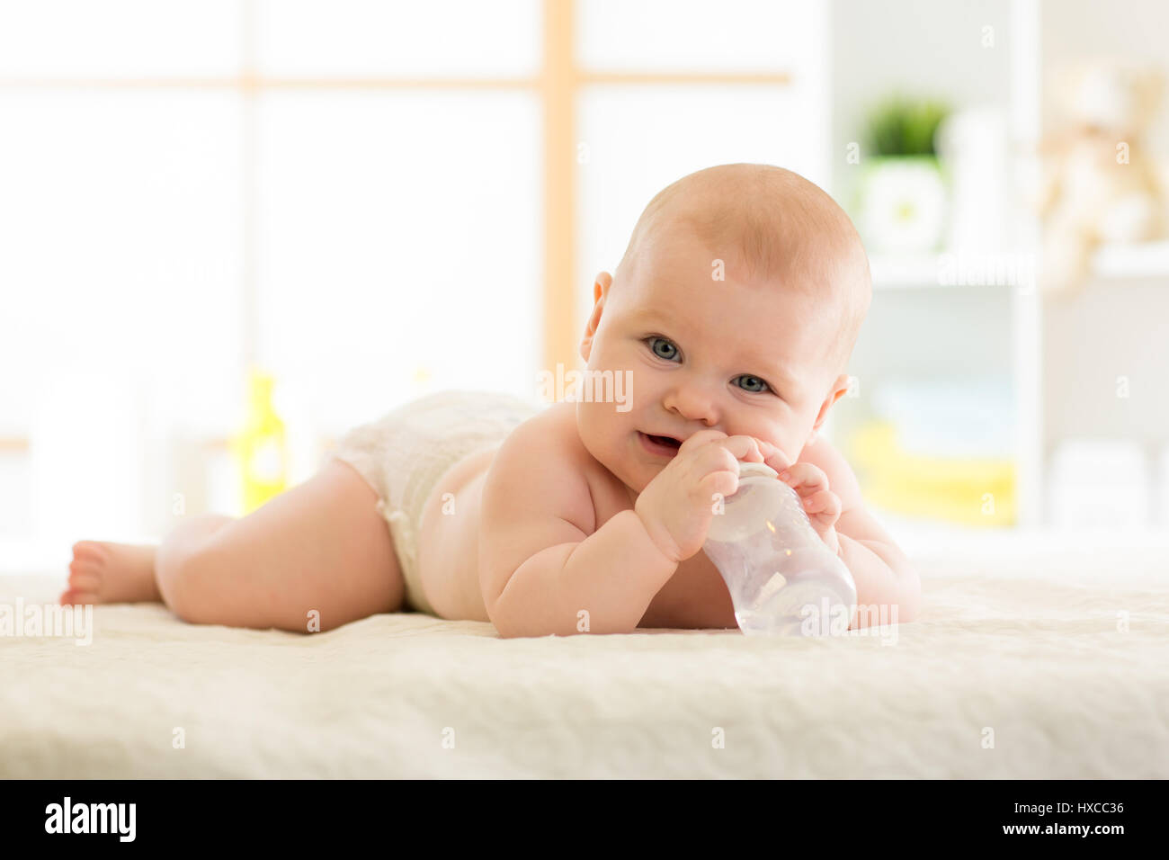 Niedliche Baby mit Flasche auf Bett Stockfoto