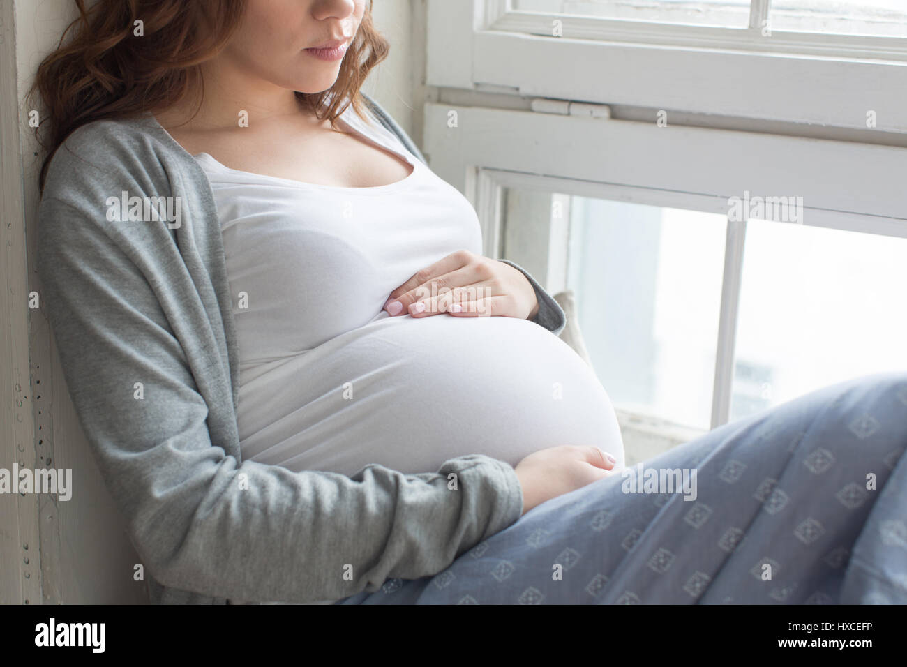 Die schwangere Bauch auf der Fensterbank Stockfoto