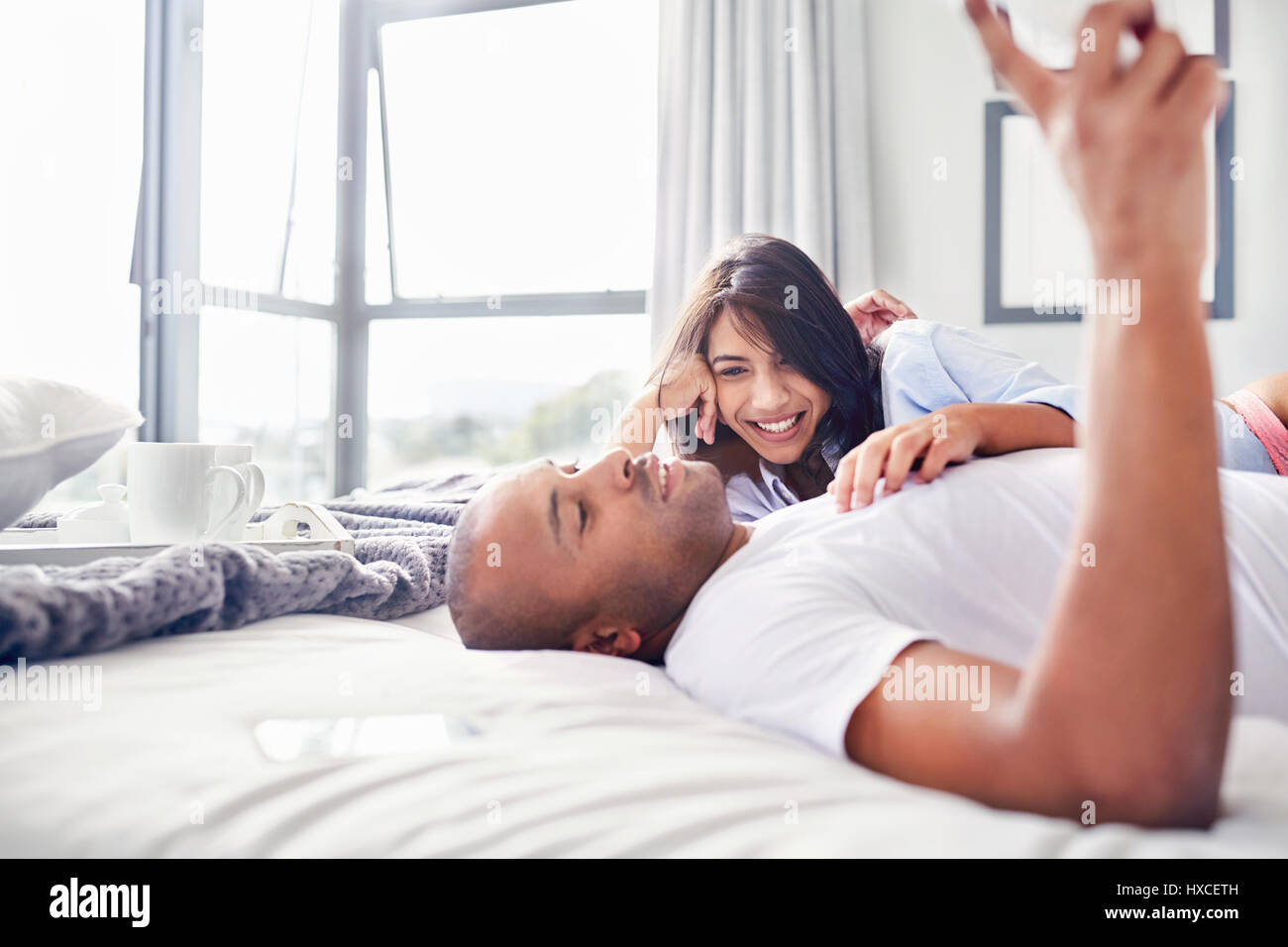 Lächelndes Paar Festlegung und Entspannung auf Bett Stockfoto