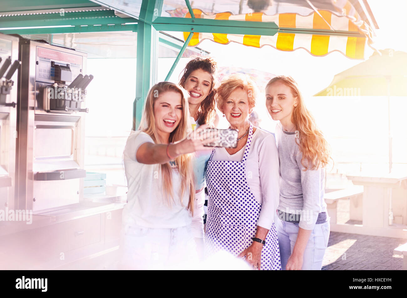 Junge Frauen, die selfie mit Senior Business Eigentümer außerhalb sonnigen Essen Warenkorb Stockfoto