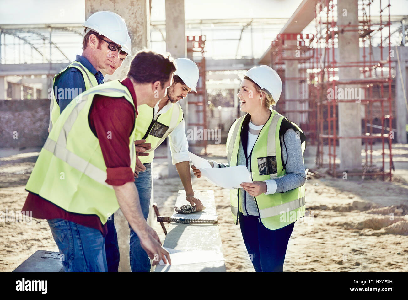 Weibliche Meister im Gespräch mit Bauarbeiter bei sonnigen Baustelle Stockfoto