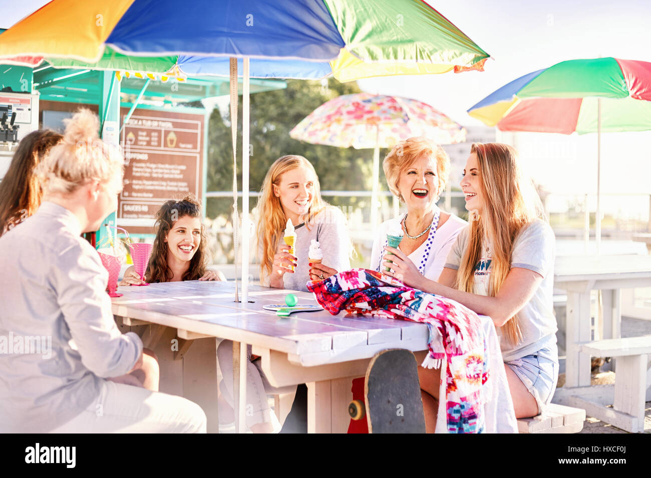 Gerne Frauen essen Eis am sonnigen boardwalk Picknick Tisch Stockfoto
