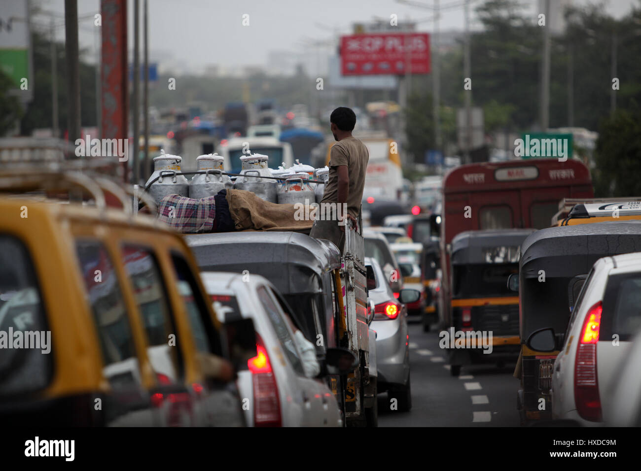 Stau mit einem Milchmann, stehend auf seinem van während einem trüben regnerischen Tag in Indien. Stockfoto