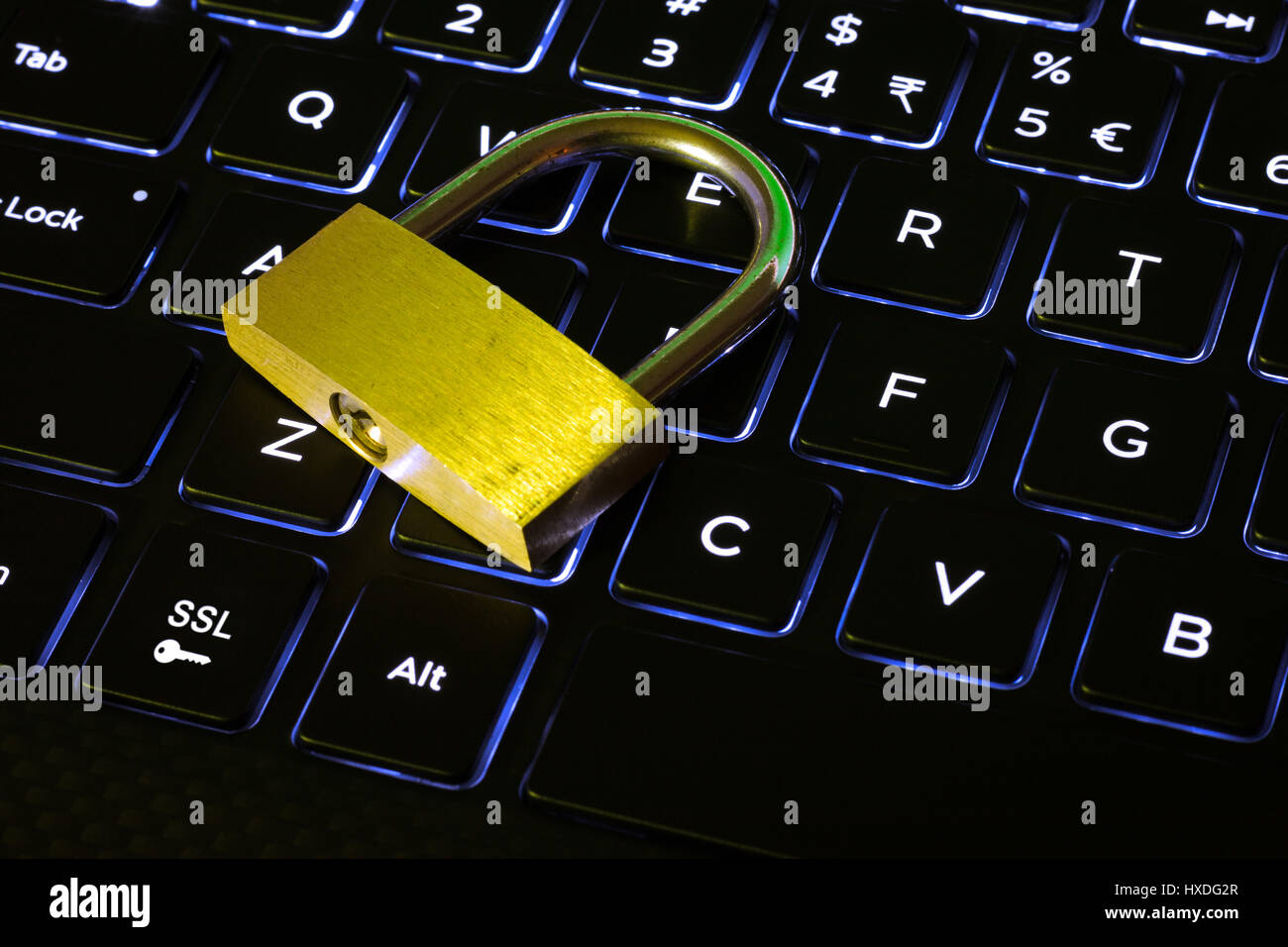Geschlossenes Vorhängeschloss und SSL-Schlüssel auf eine Computer-Tastatur mit Hintergrundbeleuchtung Stockfoto
