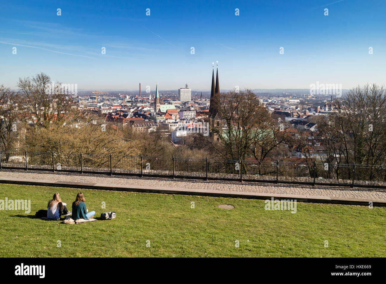 Zwei Frauen entspannen Sie sich in der Frühlingssonne auf Sparrenburg, Bielefeld, Deutschland, mit Blick auf die Stadt Stockfoto