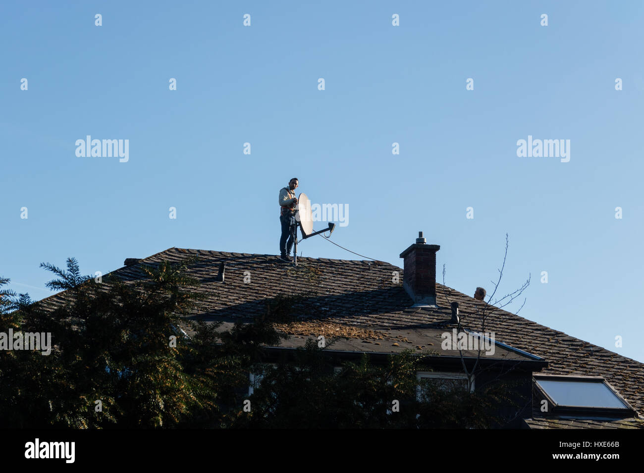 Sat-Schüssel Ingenieur steht auf Dach Satellitenschüssel installieren Stockfoto