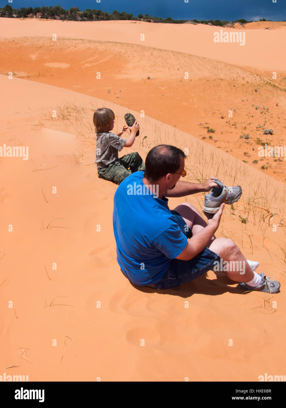 Vater und Sohn leeren Sie den Sand aus ihren Schuhen im Coral Pink Sand Dunes State Park in Utah. Stockfoto