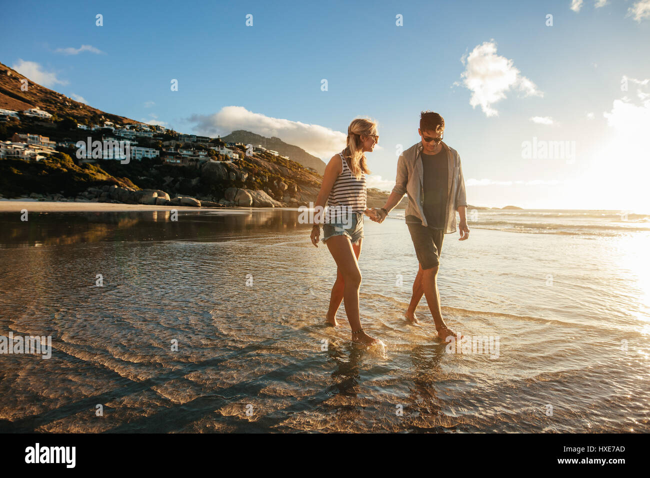 Voller Länge Schuss junges Paar Hand in Hand am Strand. Junger Mann und Frau ein Spaziergang am Ufer Meeres. Stockfoto
