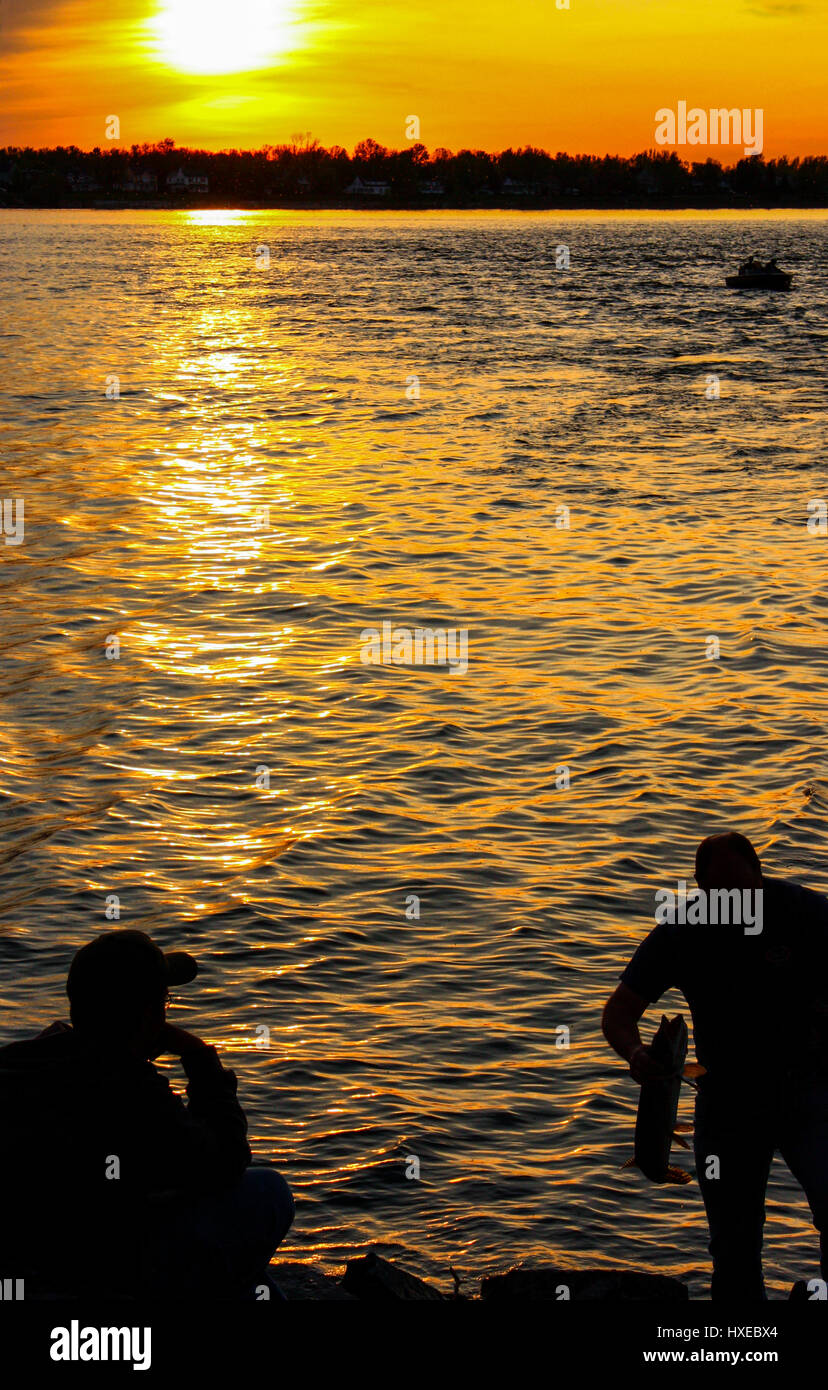 Silhouette-Mann mit einem Fisch in seine Hände mit einem Sonnenuntergang Stockfoto