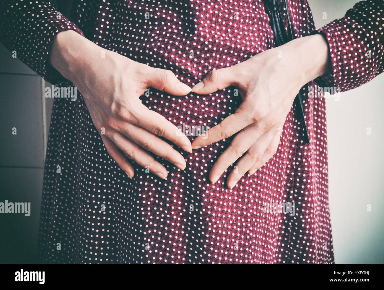 Schwangere Frau macht Herzform mit die Hände auf den Bauch Stockfoto