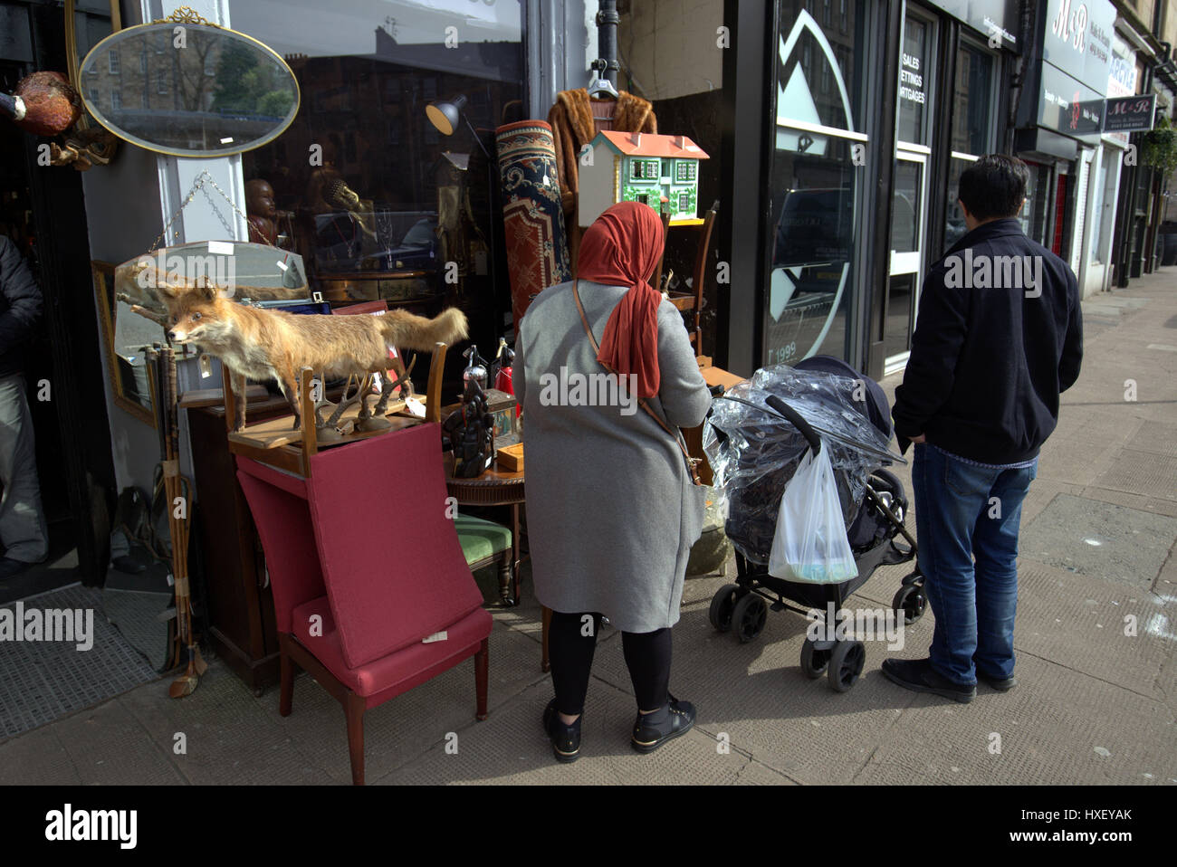 Asiatische Familie Flüchtling gekleidet Hijab Schal auf Straße in der UK alltägliche Szene Trödelladen oder Antiquitätengeschäft Fuchs Stockfoto