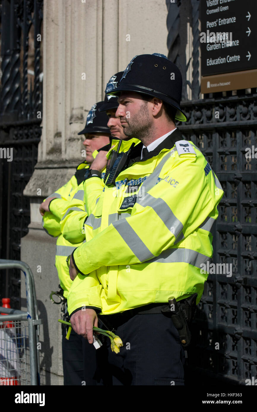 Polizist hält Blumen am Tor zu den Westminster-Palast nach Westminster Terroranschlag in London, Vereinigtes Königreich. Stockfoto