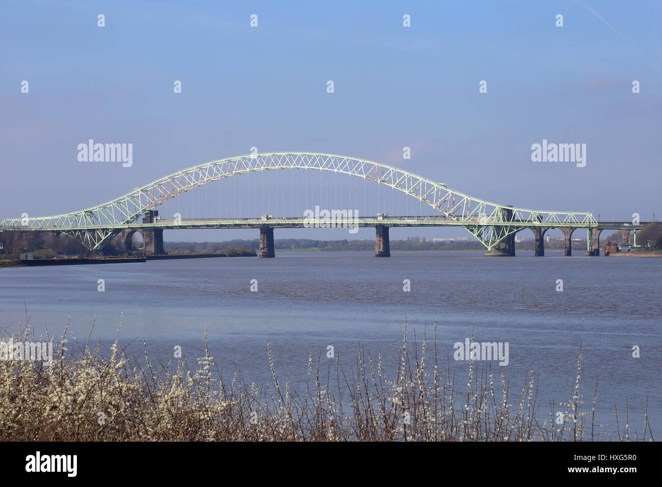 Die Silver Jubilee Bridge in Runcorn überqueren den Manchester Ship Canal und den Fluss Mersey. Eisenbahnbrücke der Steinbau mit Säulen befindet sich hinter Stockfoto