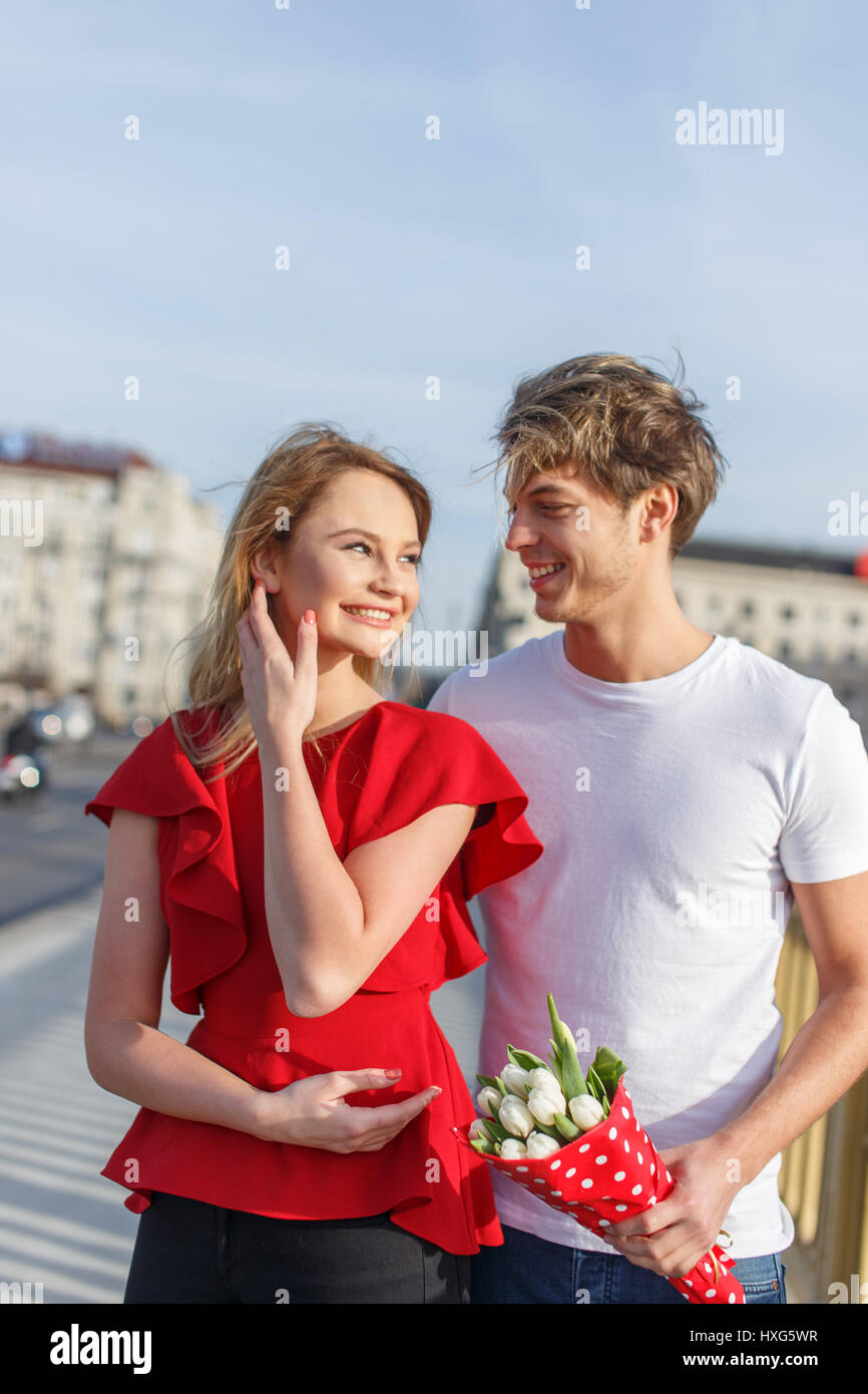 Junges Paar aus dem outdoor, Frau im roten Kleid bekommen Strauß Stockfoto