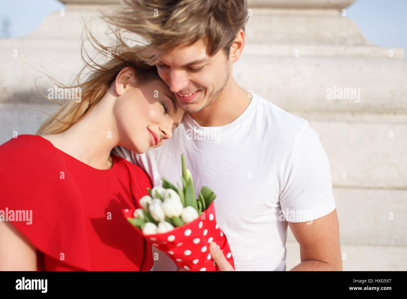 Junge Frau im roten Kleid kuscheln zu Mann, wenn dating, träumen von Liebe Stockfoto