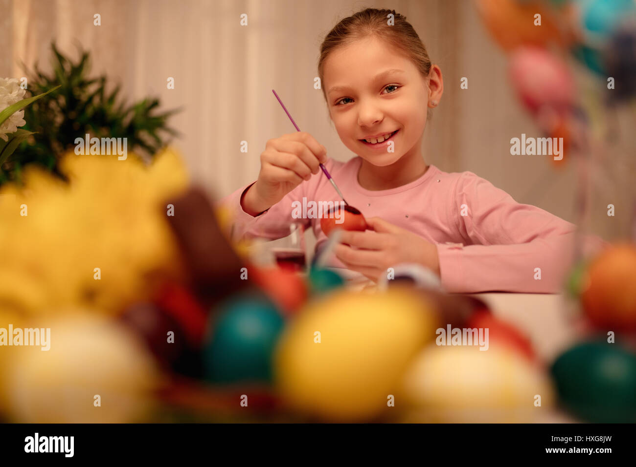 Süß lächelnd kleine Mädchen Malerei Osterei zu Hause. Blick in die Kamera. Stockfoto