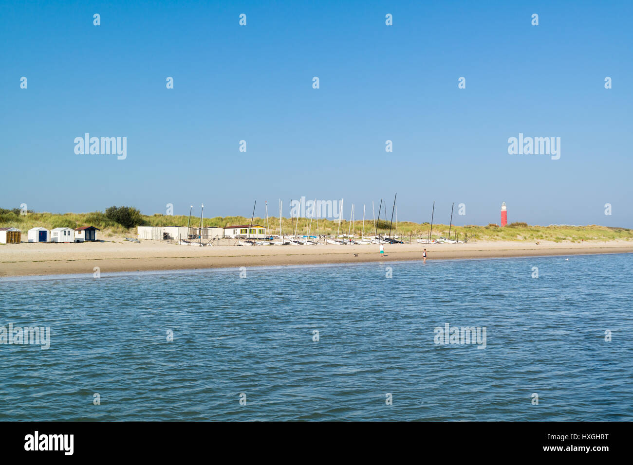 Küste von West friesischen Wattenmeer Insel Texel mit Strandhütten, Booten, Personen und Leuchtturm von De Cocksdorp, Niederlande Stockfoto