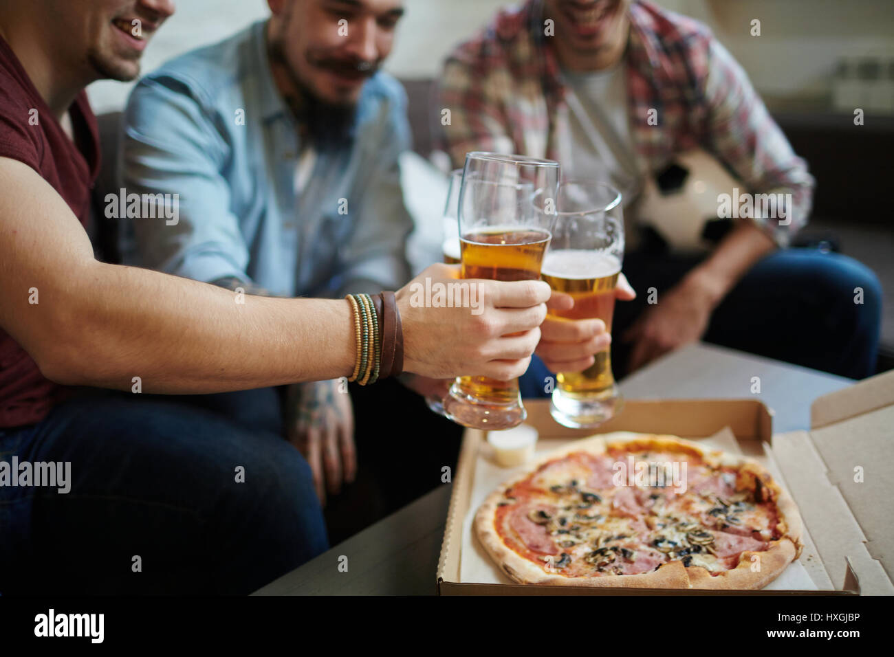 Closeup Portrait Gruppe von Freunden treffen zu Hause Toasten mit Bier und Pizza essen, beim Fußballspiel ansehen Stockfoto