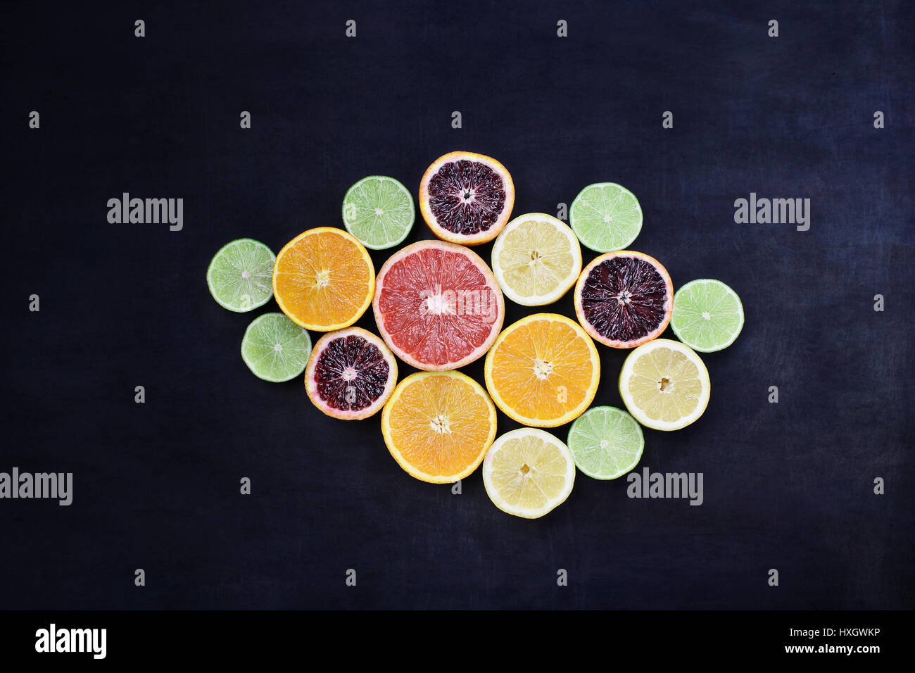 Vielzahl von Zitrusfrüchte (Orange, Blutorangen, Zitronen, Grapefruit und Limetten) über einem schwarzen rustikalen Hintergrund. Bild von oben. Stockfoto