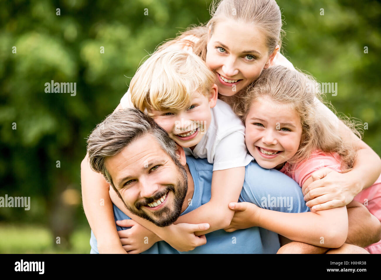 Glückliche Familie mit zwei Kindern umarmt zusammen in Harmonie im Garten Stockfoto