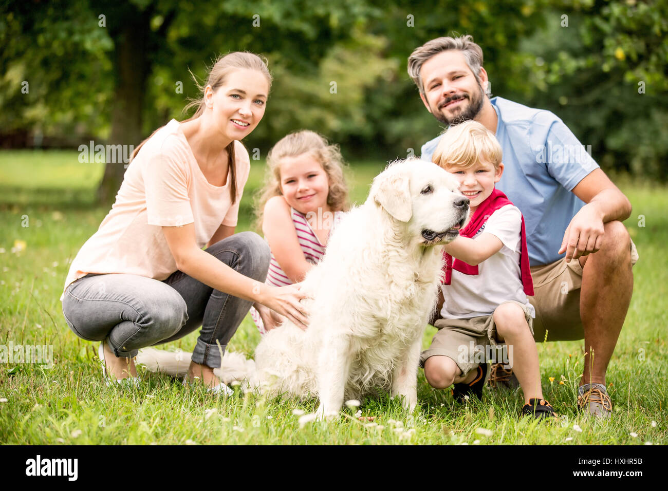 Glückliche Familie mit Kindern und Hund zusammen im Garten im Sommer Stockfoto