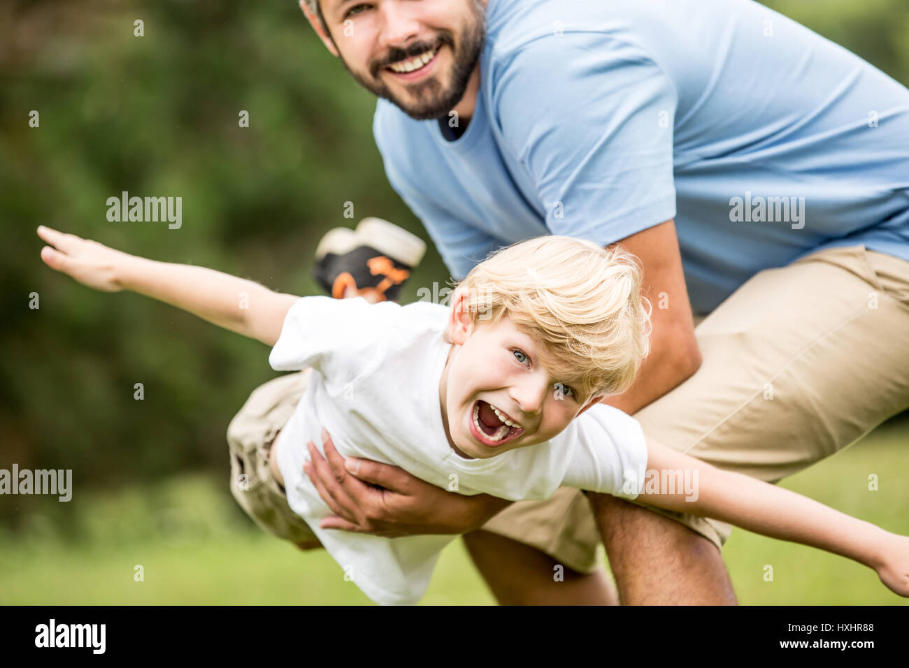 Kinder lachen und spielen mit Vater Spaß im Sommer Stockfoto
