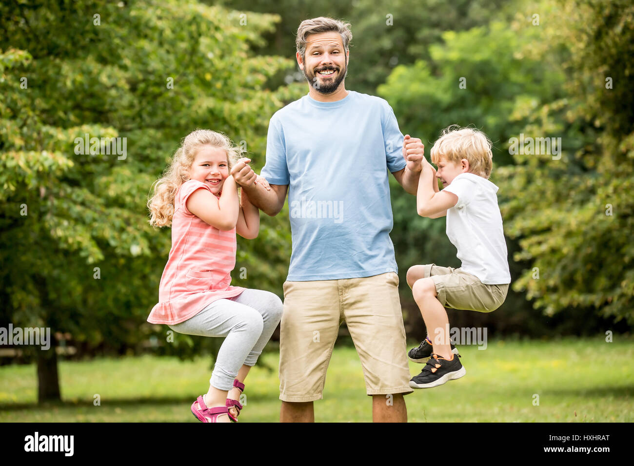 Kinder toben mit Vater spielen und haben Spaß im park Stockfoto